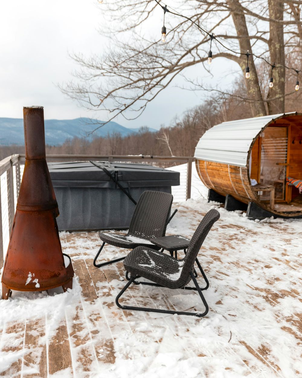 A covered hot tub on a wooden deck after a fresh snowfall
